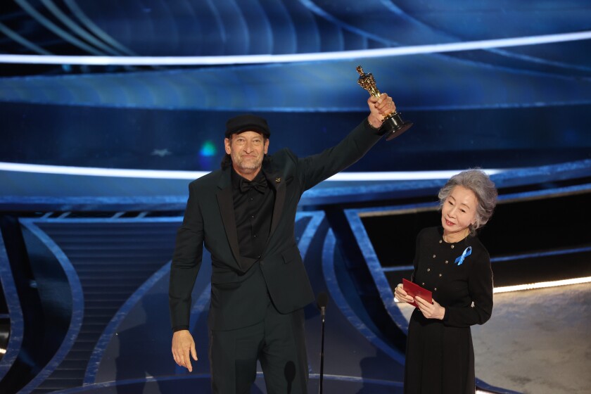 Troy Kotsur accepts the Actor in a Supporting Role award for ‘CODA’ from Yuh-jung Youn at the 94th Academy Awards.