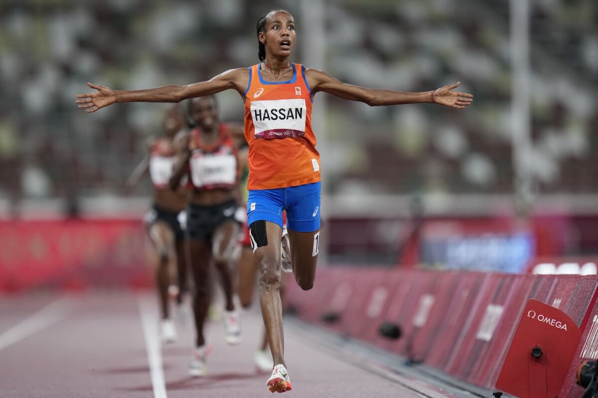 Netherlands' Sifan Hassan holds her arms out at her sides as she crosses the finish line ahead of other runners
