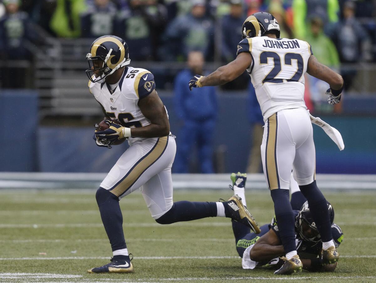 Rams linebacker Akeem Ayers (56) runs with the ball as he heads to score a touchdown on a fumble recovery, followed by teammate Trumaine Johnson (22) and Seattle Seahawks' Kevin Smith on Dec. 27, 2015.