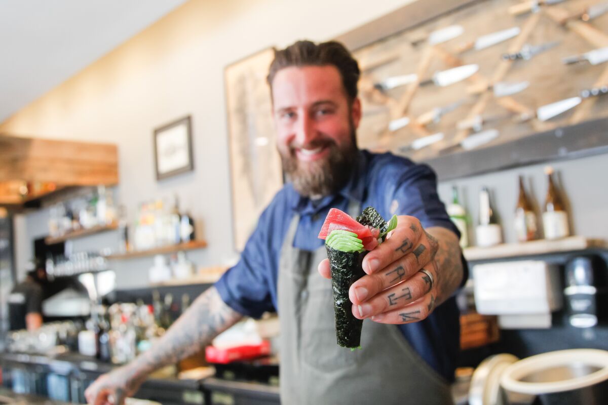 Chef Rob Ruiz displays a sushi hand roll like the ones he plans to serve at The Hold Fast, a booth serving fresh-caught San Diego seafood that will open this fall in Liberty Public Market at Liberty Station.
