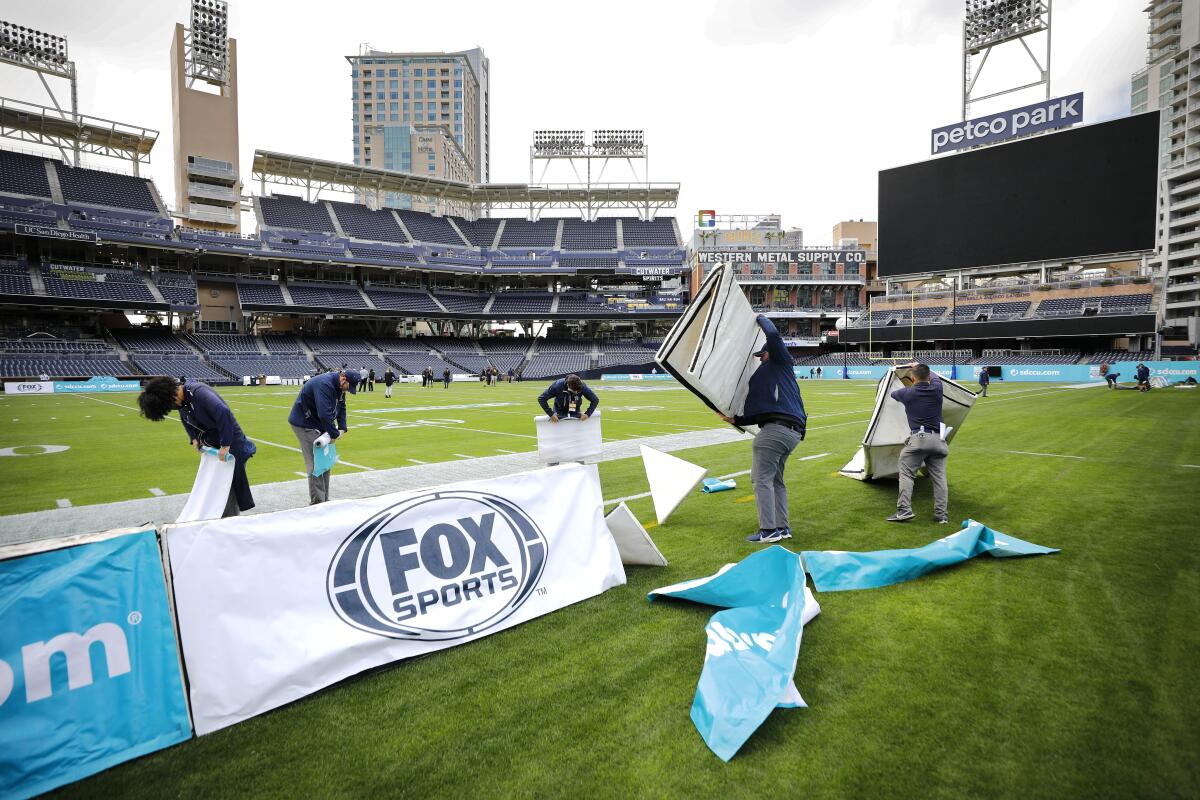 Workers take down sideline signage at Petco Park after the Holiday Bowl was cancelled hours before kick-off. 