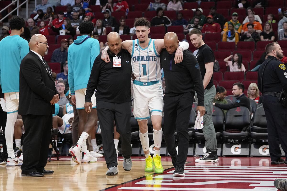 Charlotte Hornets' LaMelo Ball (1) is helped off the court after being injured during the second half of an NBA basketball game against the Houston Rockets Wednesday, Jan. 18, 2023, in Houston. The Hornets won 122-117. (AP Photo/David J. Phillip)