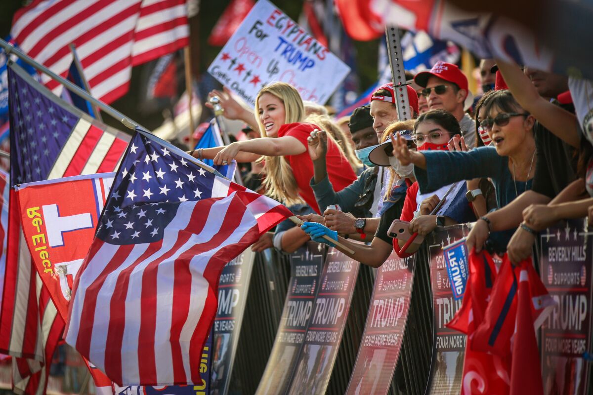 Trump supporters cheer and wave at passing vehicles while attending the USA Freedom Rally in Beverly Gardens Park