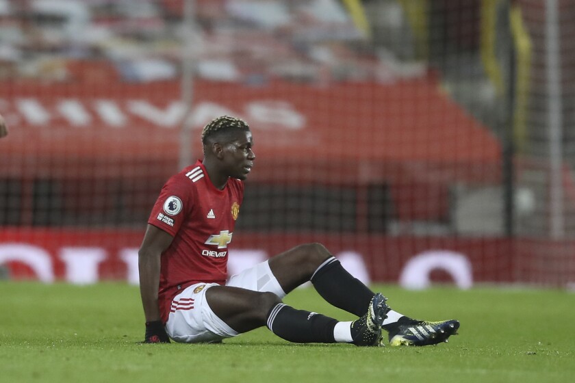 Manchester United's Paul Pogba sits on the ground after getting injured during an English Premier League soccer match between Manchester United and Everton at the Old Trafford stadium in Manchester, England, Saturday Feb. 6, 2021. (Martin Rickett/Pool via AP)
