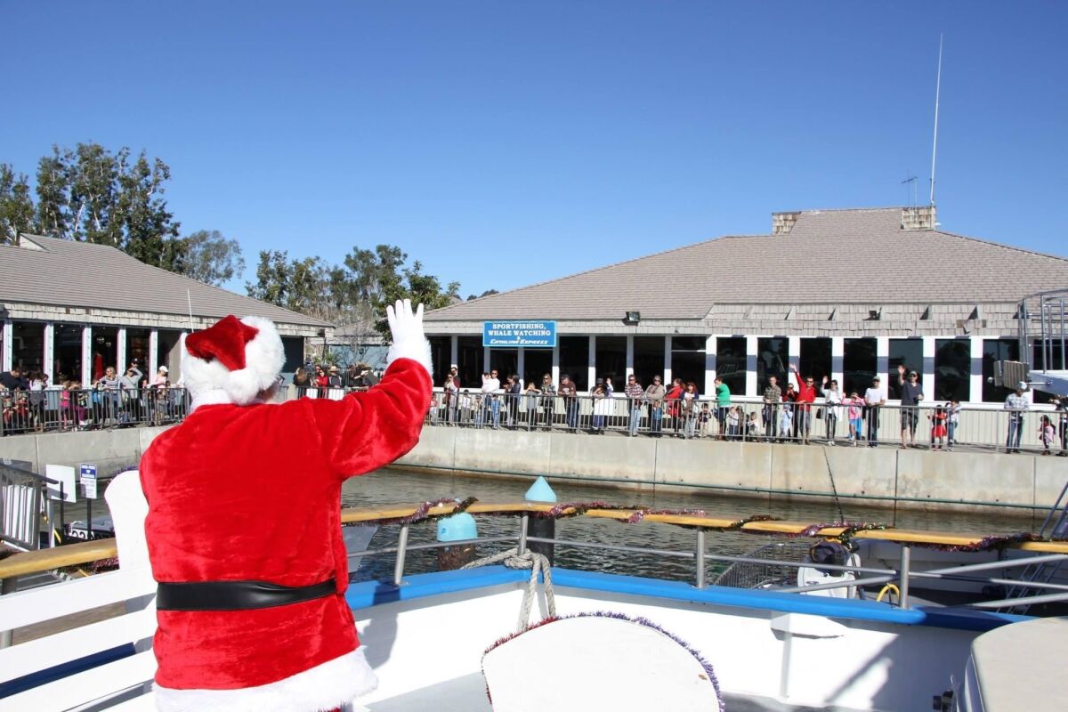 Santa waves from a boat at Dana Wharf