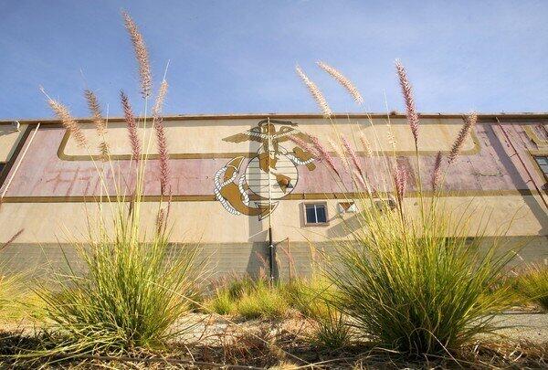 Even though weeds are invading the area, the eagle, globe and anchor insignia of the Marine Corps is still visible on some of the buildings on the old El Toro Marine Base in Irvine where the city is slowly building its Great Park.