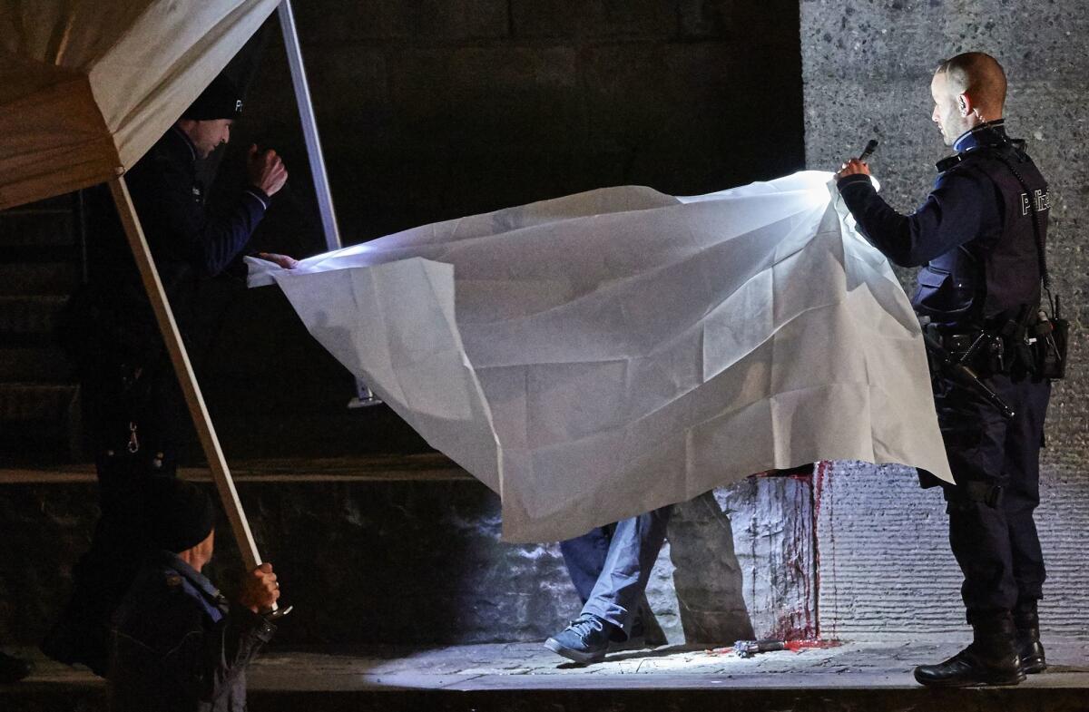 Swiss police officers hold a blanket to cover a body found near a mosque in central Zurich, after a Dec. 19 attack by a gunman.