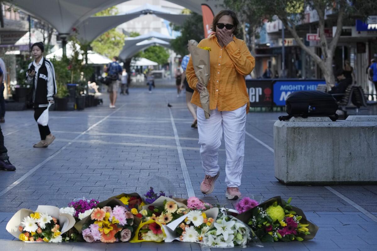 A woman brings flowers to an impromptu memorial at Bondi Junction in Sydney, Sunday, April 14, 2024, after several people were stabbed to death at a shopping center Saturday. (AP Photo/Rick Rycroft)