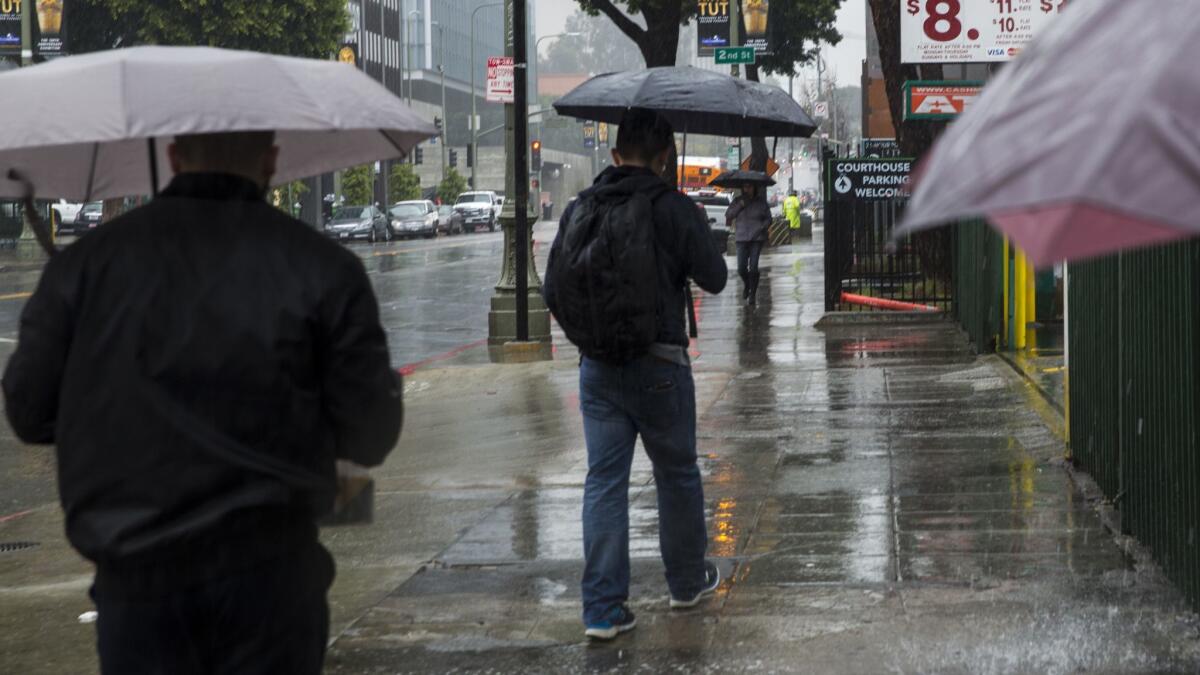 Pedestrians walk quickly in the rain in early March in downtown Los Angeles. Additional storms are expected into next week.