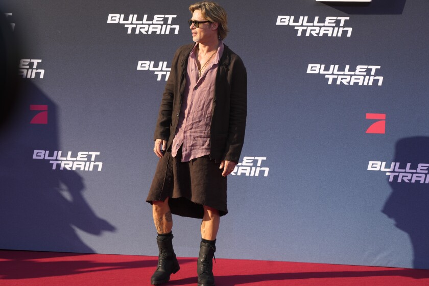 Brad Pitt wears a skirt and boots on a red carpet