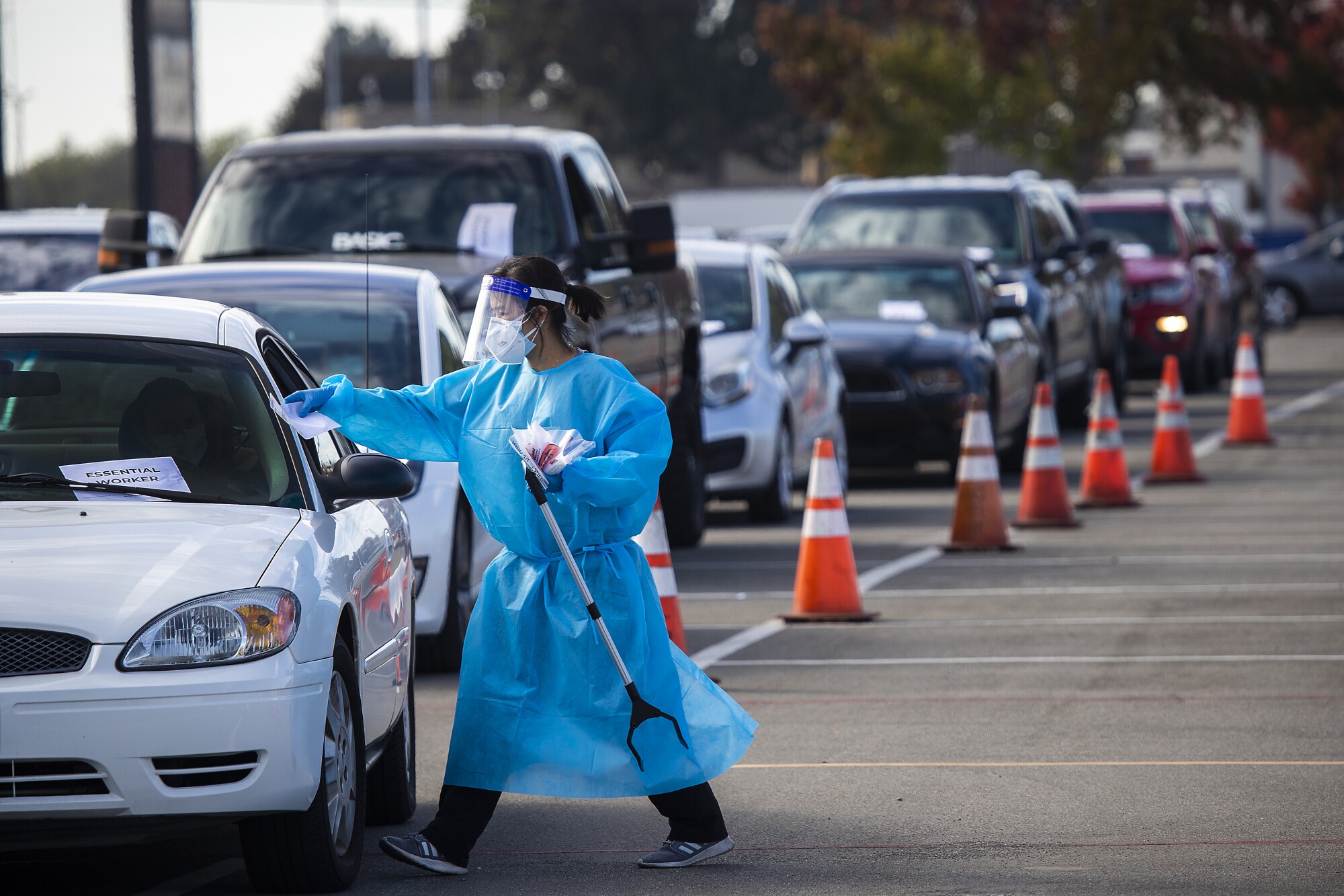 A healthcare worker conducts coronavirus test at a drive-through site in Costa Mesa.