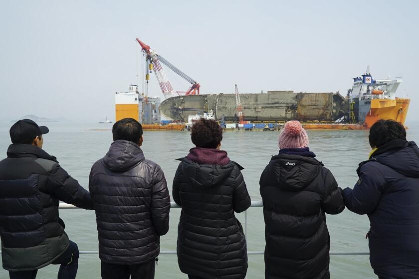 Families of three missing victims look at the retrieved Sewol ferry on a semisubmersible transport vessel in the waters near Jindo, South Korea on Tuesday.