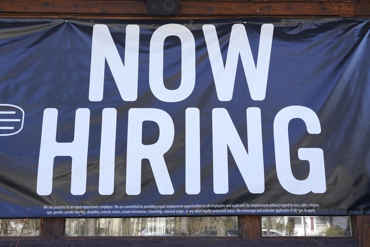A "Now Hiring" sign outside a restaurant