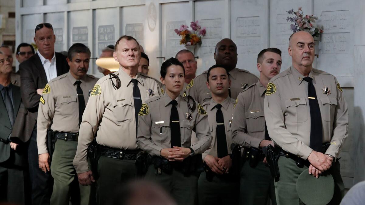 Sheriff's Department officials listen to the Rev. Kimball Coburn speak during retired Sheriff's Deputy Steven Belanger's funeral.