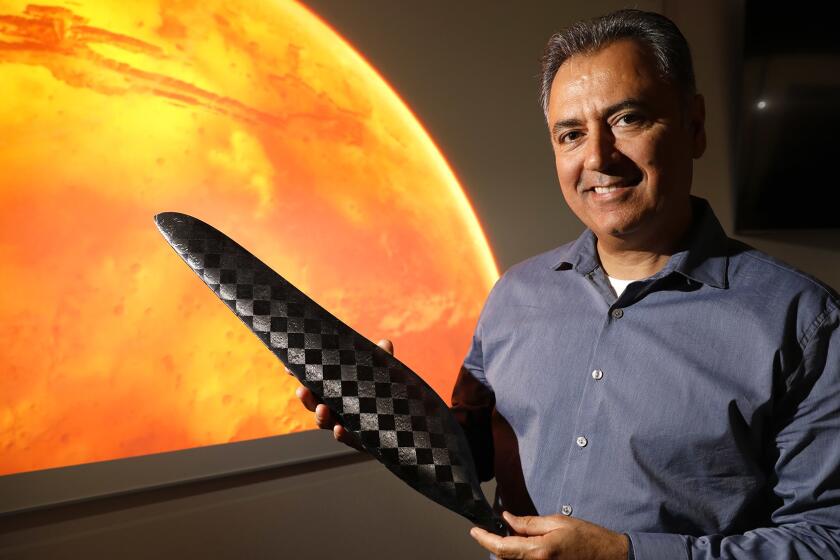 Wahid Nawabi, chief executive of AeroVironment Inc., holds a scale model of one of the composite blades that will be used to propel NASA's Jet Propulsion Laboratory Mars Helicopter through the thin Martian atmosphere.