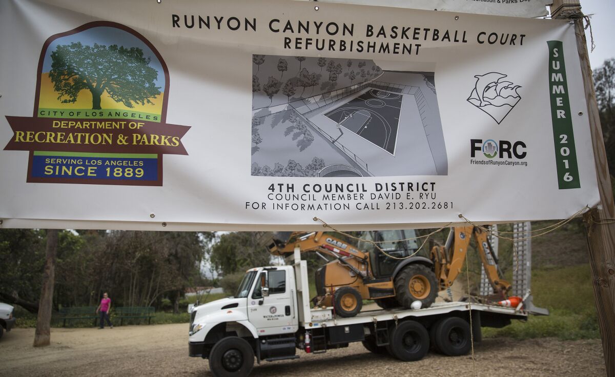A sign in Runyon Canyon park touts the construction of a basketball court. Neighbors of the park are seeking to stop the court from being built.