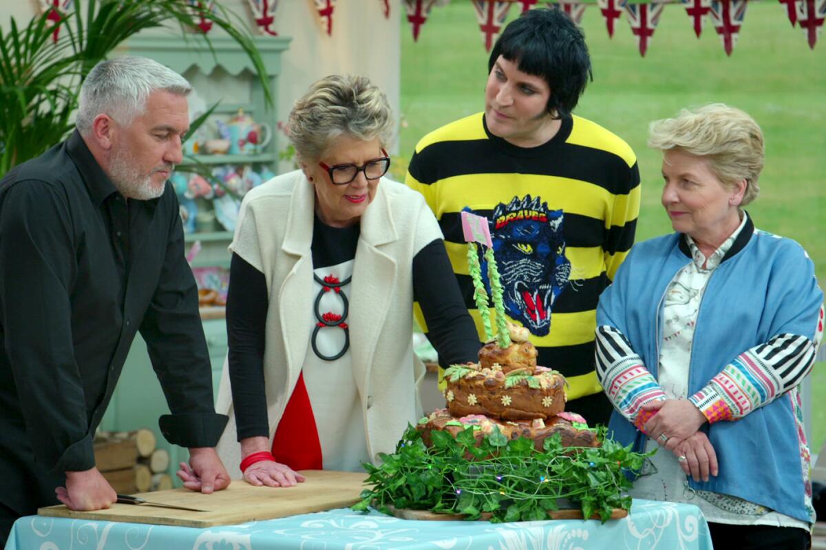 Four people stand around an elaborate tiered cake