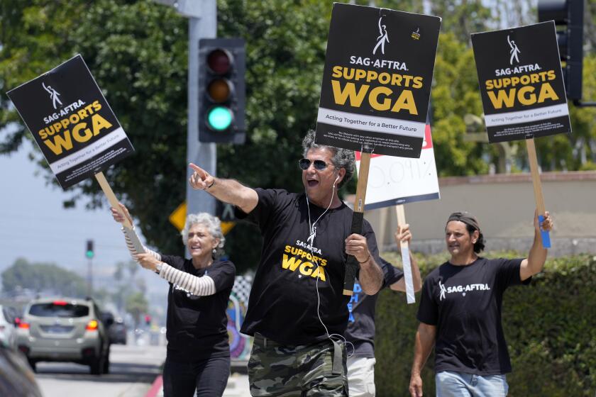 Screen Actors Guild member Dereck Andrade, center, and other SAG members take part in a Writers Guild rally outside Warner Bros. Studios, Monday, May 22, 2023, in Burbank, Calif. (AP Photo/Chris Pizzello)