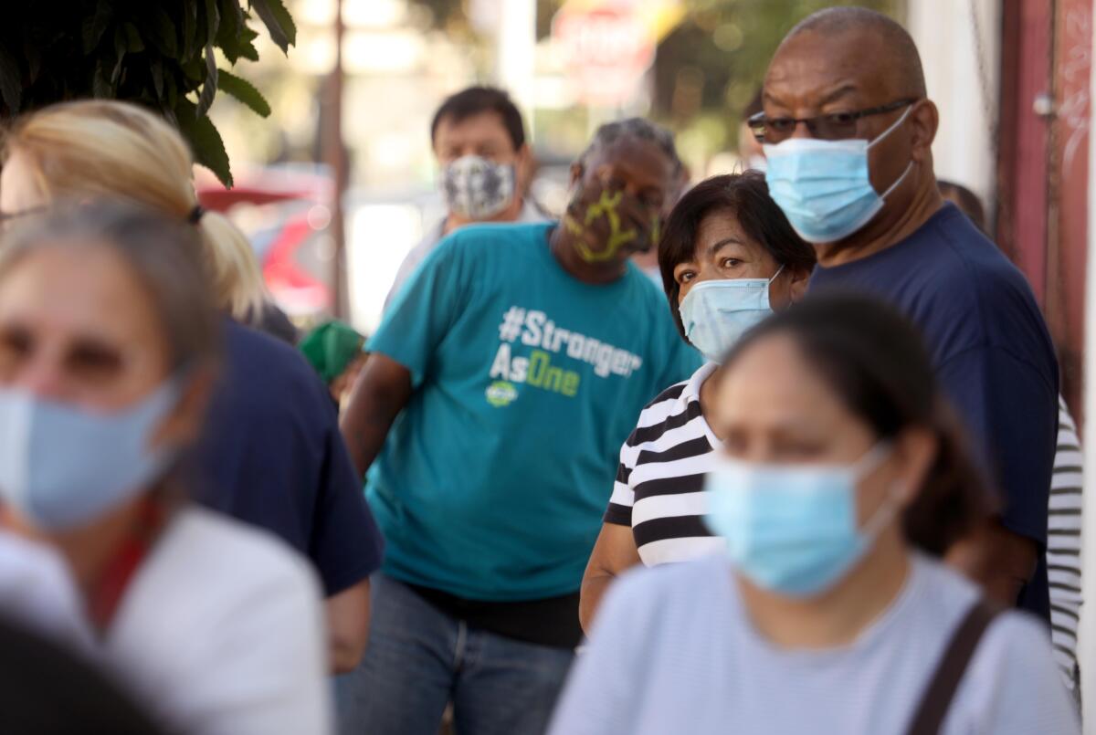 People in masks wait in line