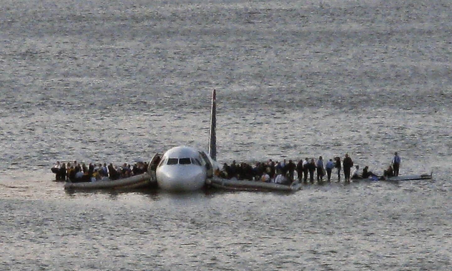 Airline passengers wait on the wings of a US Airways Airbus A320 to board a ferry after the jetliner safely landed in the Hudson River in New York.