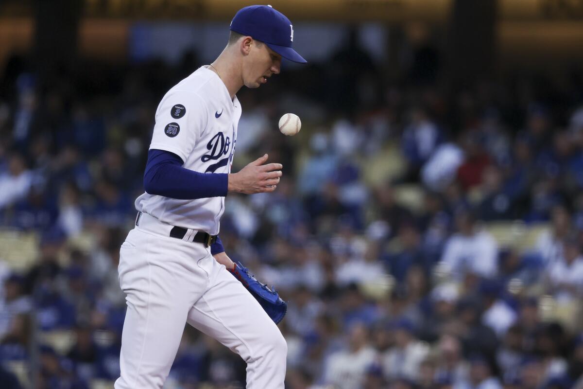 Dodgers starting pitcher Walker Buehler tosses a baseball while on the mound against the Giants.