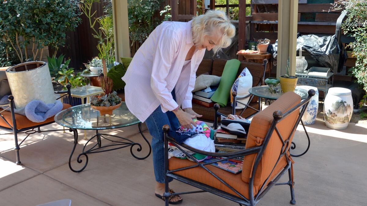 A woman sorts through items on a chair. 