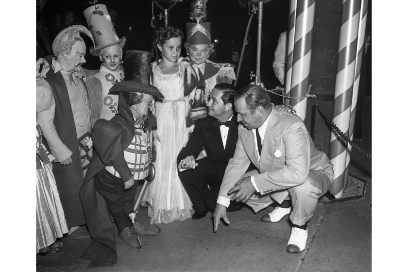 Aug. 15, 1939: Surrounded by Munchkins from the âWizard of Oz,â Carrol Ann Beery enjoys forecourt activities at Graumanâs Chinese premiere. Bending over are actor Wallce Beery and Mervyn LeRoy, producer of picture. This image appeared in the Aug. 16, 1939, Los Angeles Times.