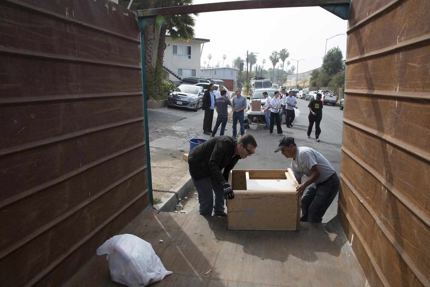Volunteers load a discarded cabinet into a dumpster as they help clean up Kingsley Street in a monthly meet-up organized by the East Hollywood Neighborhood Council on May 30, 2015.