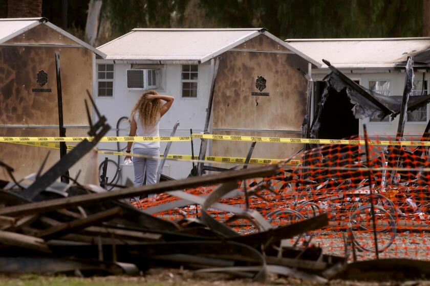WEST LOS ANGELES, CA - SEPTEMBER 9, 2022 - - A woman looks over some of the tiny home shelters that were damaged or destroyed in a fire Friday morning on the West Los Angeles Veterans Affairs campus on September 9, 2022. There were no immediate signs of foul play according to fire officials but the cause of the fire remains under investigation. The tiny homes village was erected after the VA cleared a makeshift encampment on San Vicente Boulevard in November. The West LA encampment, known as Veterans Row, was cleared last year and many of the veterans were moved into the tiny home shelters. (Genaro Molina / Los Angeles Times)