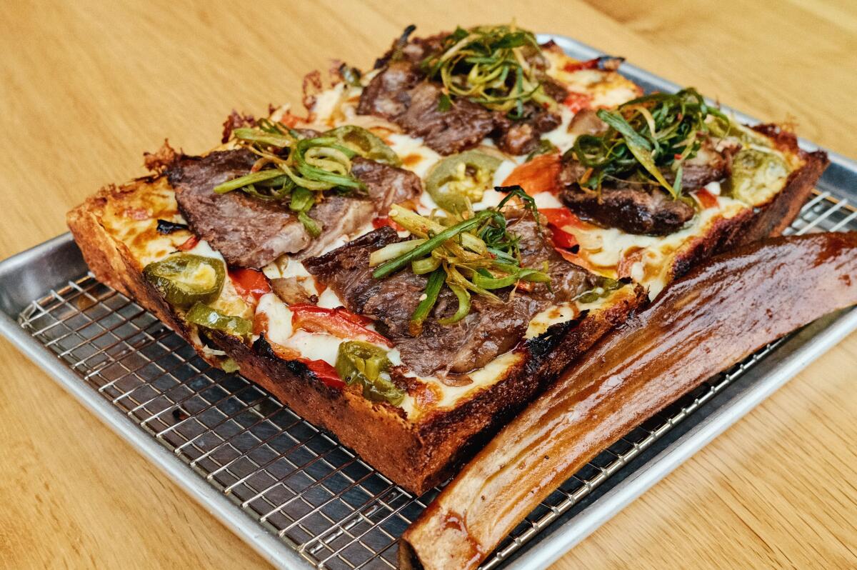 An overhead of a galbi square pizza on a table at Seven Tigers Pie Club with toppings of beef rib, peppers and green onion
