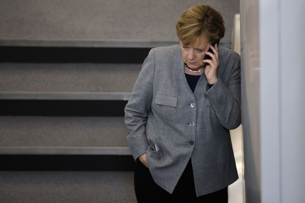 FILE -- In this Oct. 24, 2017 file photo German Chancellor Angela Merkel phones during a break of a meeting of the German parliament in Berlin, Germany. Russian pranksters posed as Ukraine’s ex-President Petro Poroshenko to reach Angela Merkel by phone and discuss Ukraine and Belarus with the former German chancellor, who appeared wary during the call. (AP Photo/Markus Schreiber, file)