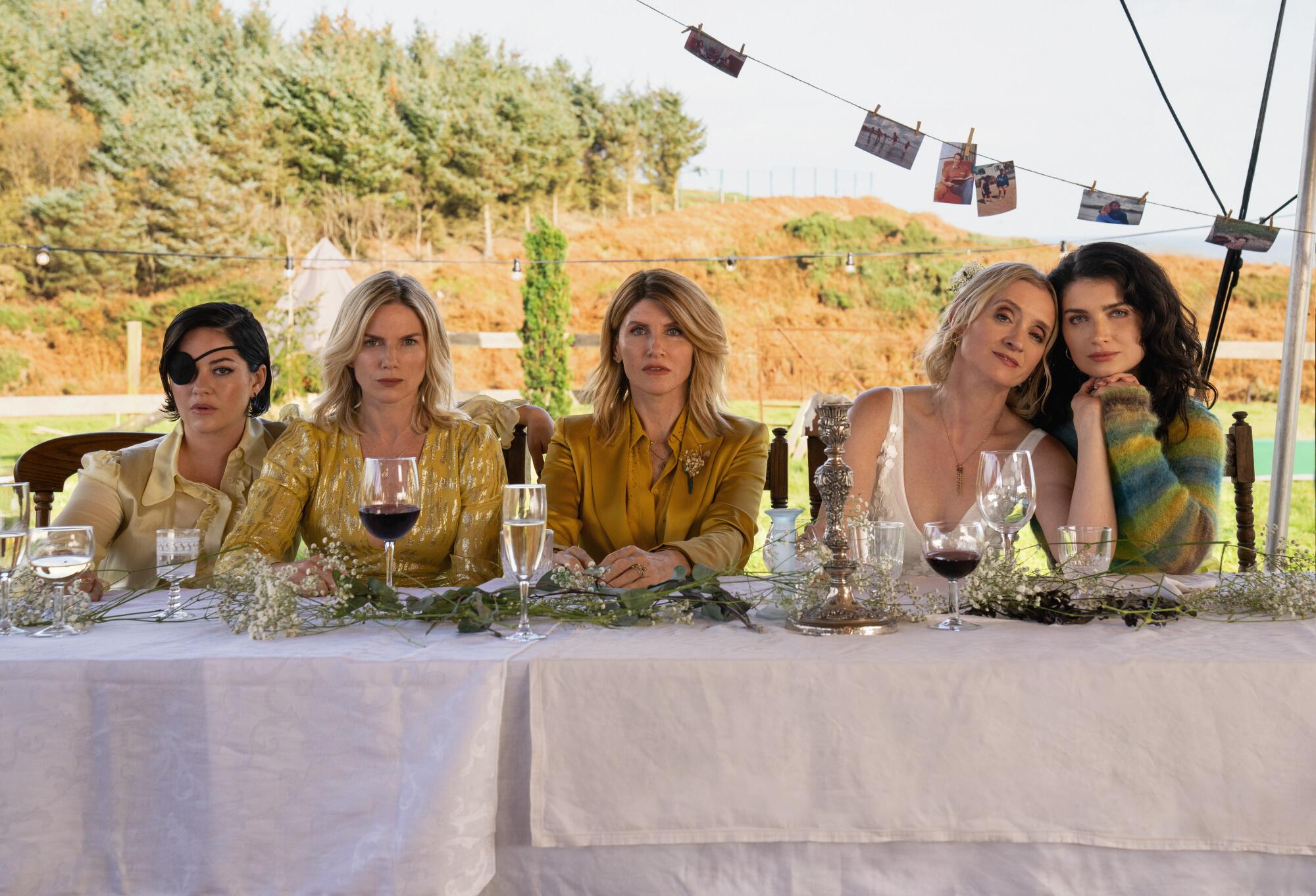 Five women seated at a long table with wine glasses in front of them.