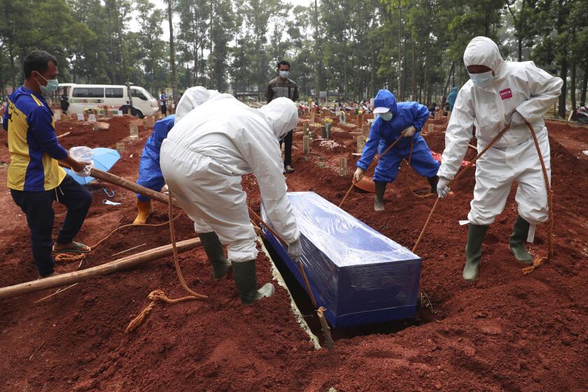 FILE - Workers in protective gear lower a coffin of a COVID-19 victim to a grave for burial at the Cipenjo Cemetery in Bogor, West Java, Indonesia, Wednesday, July 14, 2021. The World Health Organization says member countries on Saturday, June 1, 2024, approved a series of new steps to improve global preparedness for and response to pandemics like COVID-19 and mpox. (AP Photo/Achmad Ibrahim, File)