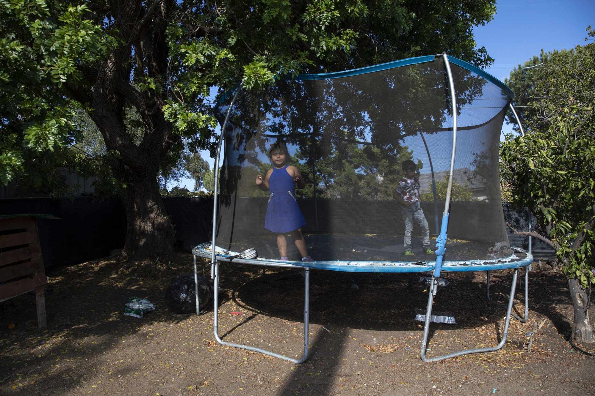  Solda 6 yaşındaki Jennifer ve 10 yaşındaki Cruz arka bahçelerinde trambolinde oynuyorlar. 