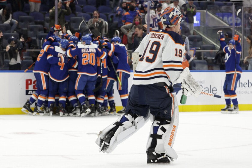 Edmonton Oilers goaltender Mikko Koskinen (19) skates off the ice as the New York Islanders celebrate an overtime goal by defenseman Noah Dobson (8) after an NHL hockey game, Saturday, Jan. 1, 2022, in Elmont, N.Y. (AP Photo/Corey Sipkin).