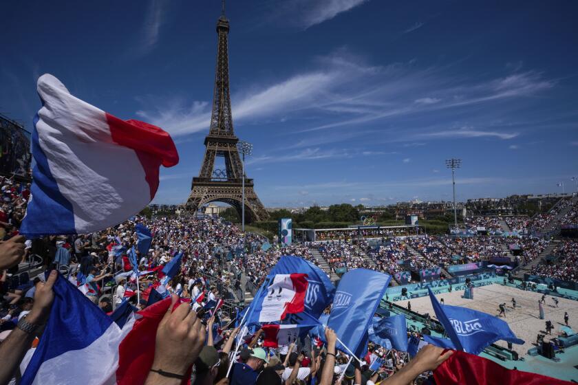 Aficionados franceses agitan banderas durante el partido entre Alemania y Francia de los Juegos Olímpicos de París frente a la Torre Eiffel, el domingo 28 de julio de 2024. (AP Foto/Louise Delmotte)