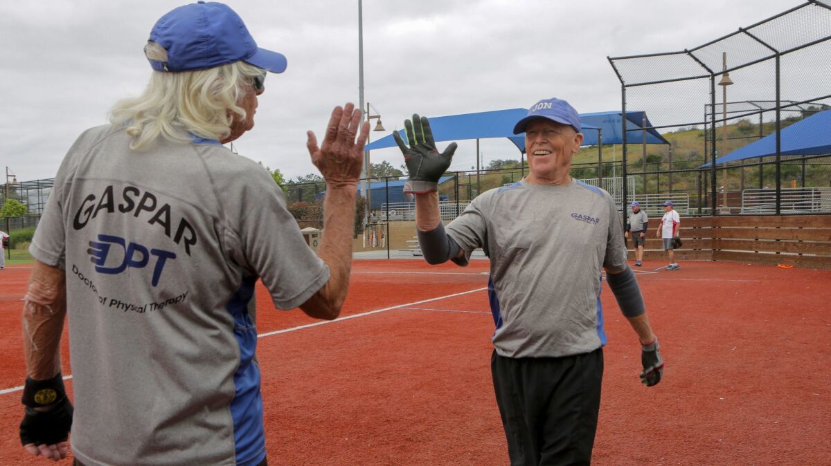 Gaspar player Jon Quinn, right, is congratulated on his inside-the-park homerun by teammate Jay Knoll, left, while playing in the North County Senior Softball league at Alga Norte Community Park in Carlsbad Thursday.