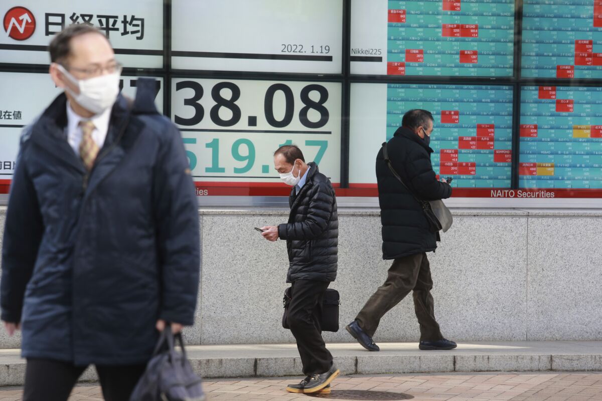 People walk by an electronic stock board of a securities firm in Tokyo, Wednesday, Jan. 19, 2022. Asian shares were lower Wednesday after a retreat on Wall Street. (AP Photo/Koji Sasahara)
