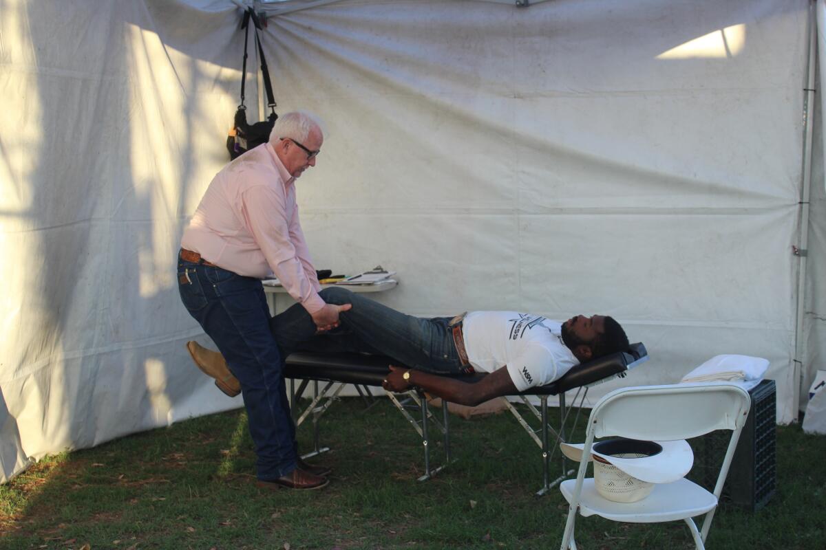 Finn Mulvaney, a chiropractor with Olde Mission Chiropractic, giving bull fighter AJ Neil an adjustment before the rodeo. 