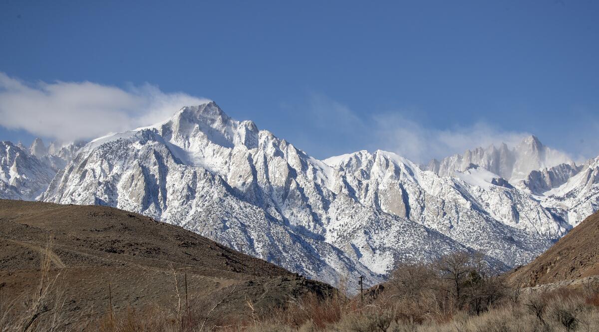 Snowy mountaintops with dry hills in the foreground