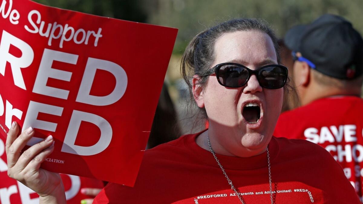 Arizona teachers shout in protest their low pay while waiting for Republican Gov. Doug Ducey on April 10 in Phoenix.