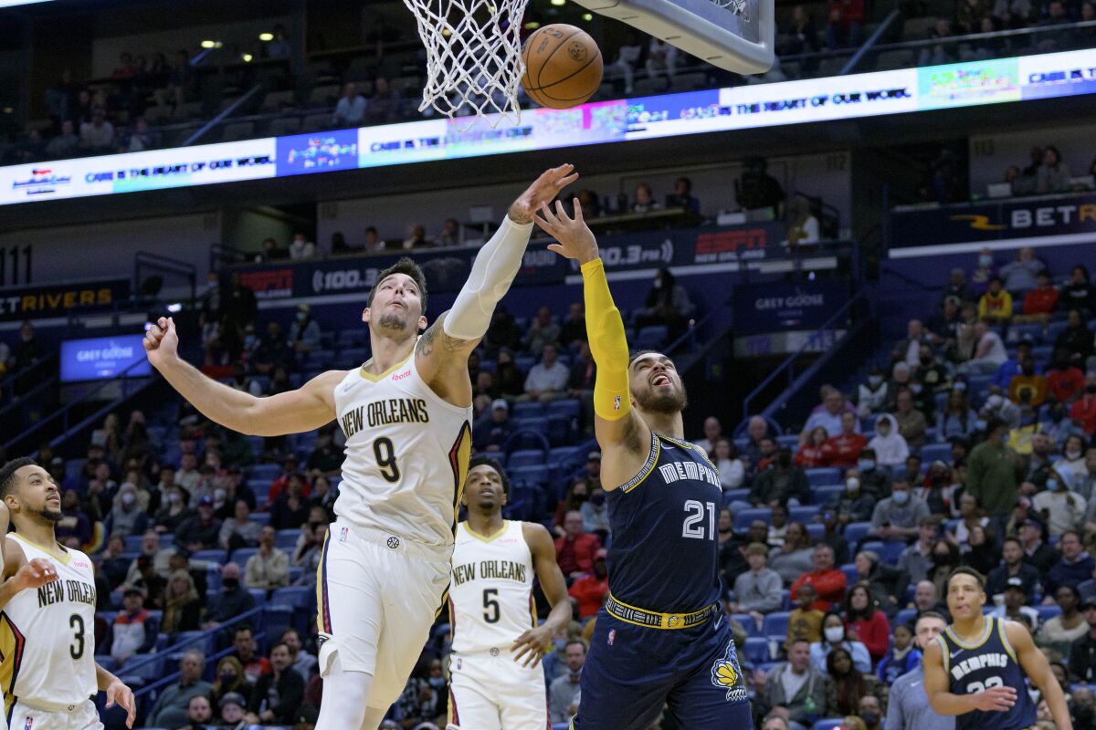 Memphis Grizzlies guard Tyus Jones (21) scores against New Orleans Pelicans center Willy Hernangomez (9) during the second half of an NBA basketball game in New Orleans, Tuesday, Feb. 15, 2022. (AP Photo/Matthew Hinton)