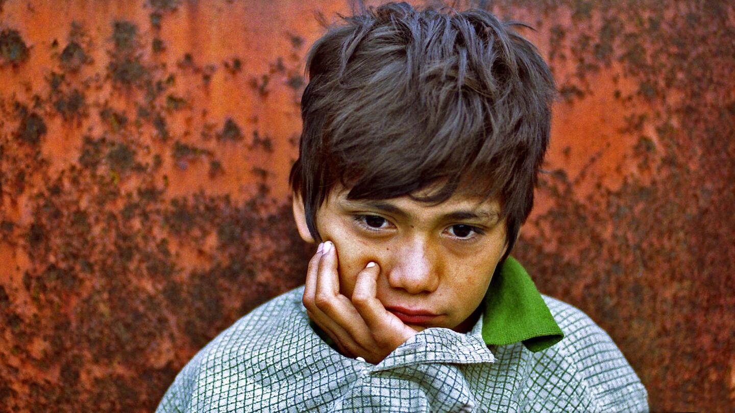 Denis Contreras, 12, awakens after sleeping in a gravel-filled hopper car in a Tapachula, Mexico, rail yard in August 2000. His mattress was crumpled paper, his blanket an oversize pullover.