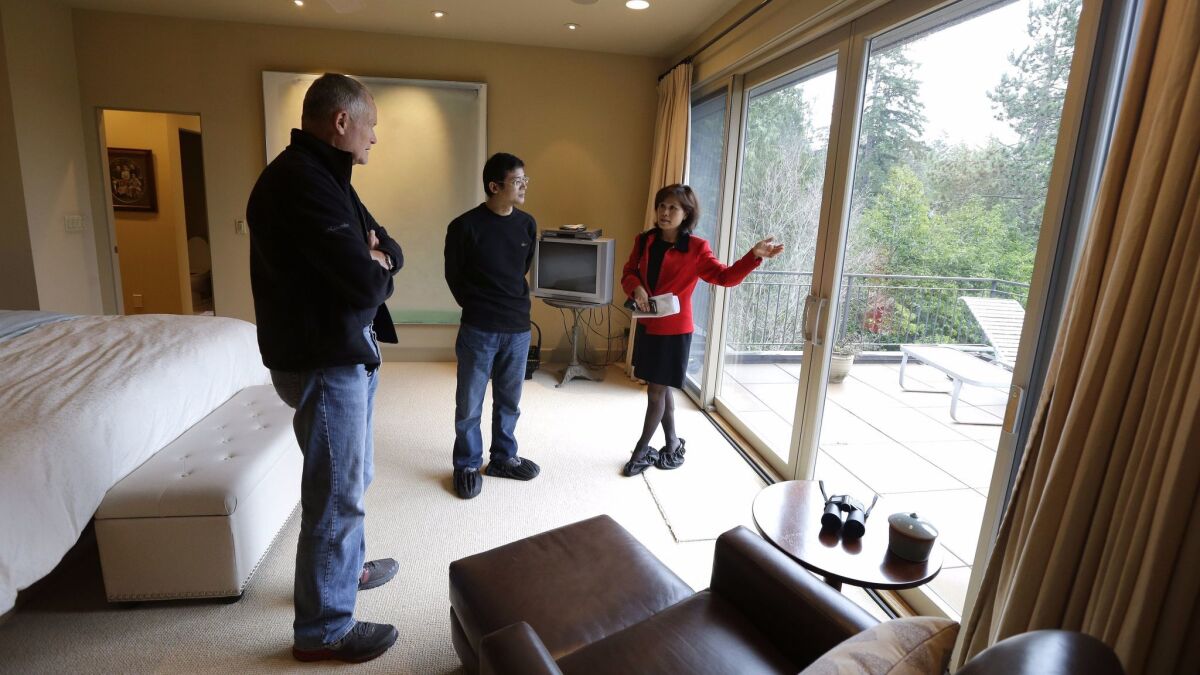 Real estate agent Janie Lee, right, shows a home in Washington state to Hongbin Wei, center, of Beijing, in 2014. In the 12 months that ended in March, international buyers purchased a record number of U.S. homes, according to a new survey.