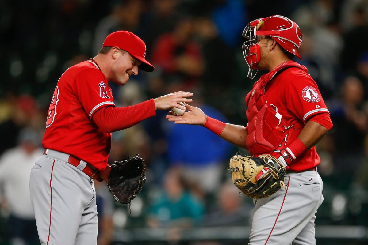 Angels reliever Joe Smith is congratulated by catcher Carlos Perez on Tuesday after a 4-3 win over the Seattle Mariners.