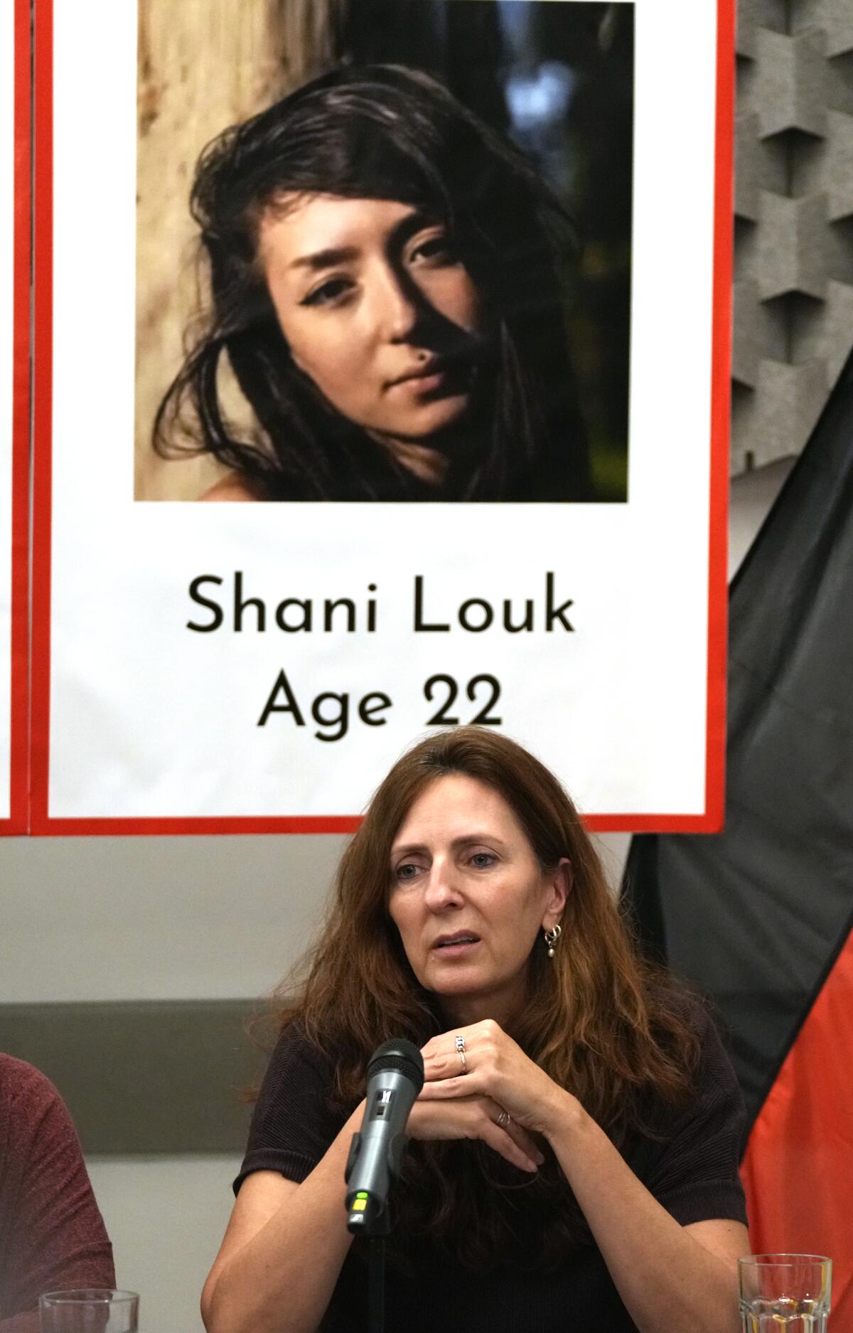 Ricarda Louk sits in front of a placard of her daughter Shani Louk.