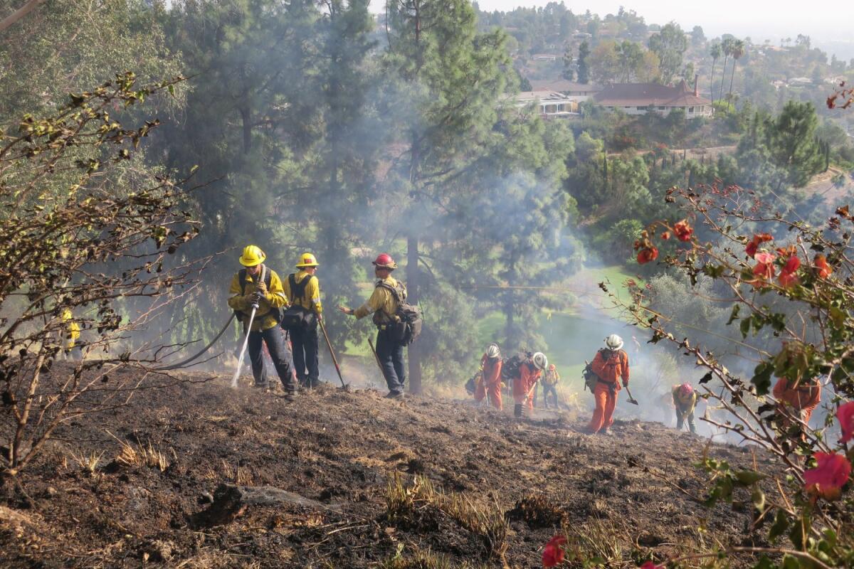 Firefighters battle a small hillside fire that broke out just before noon Thursday near the La Cañada Flintridge Country Club and threatened nearby homes.