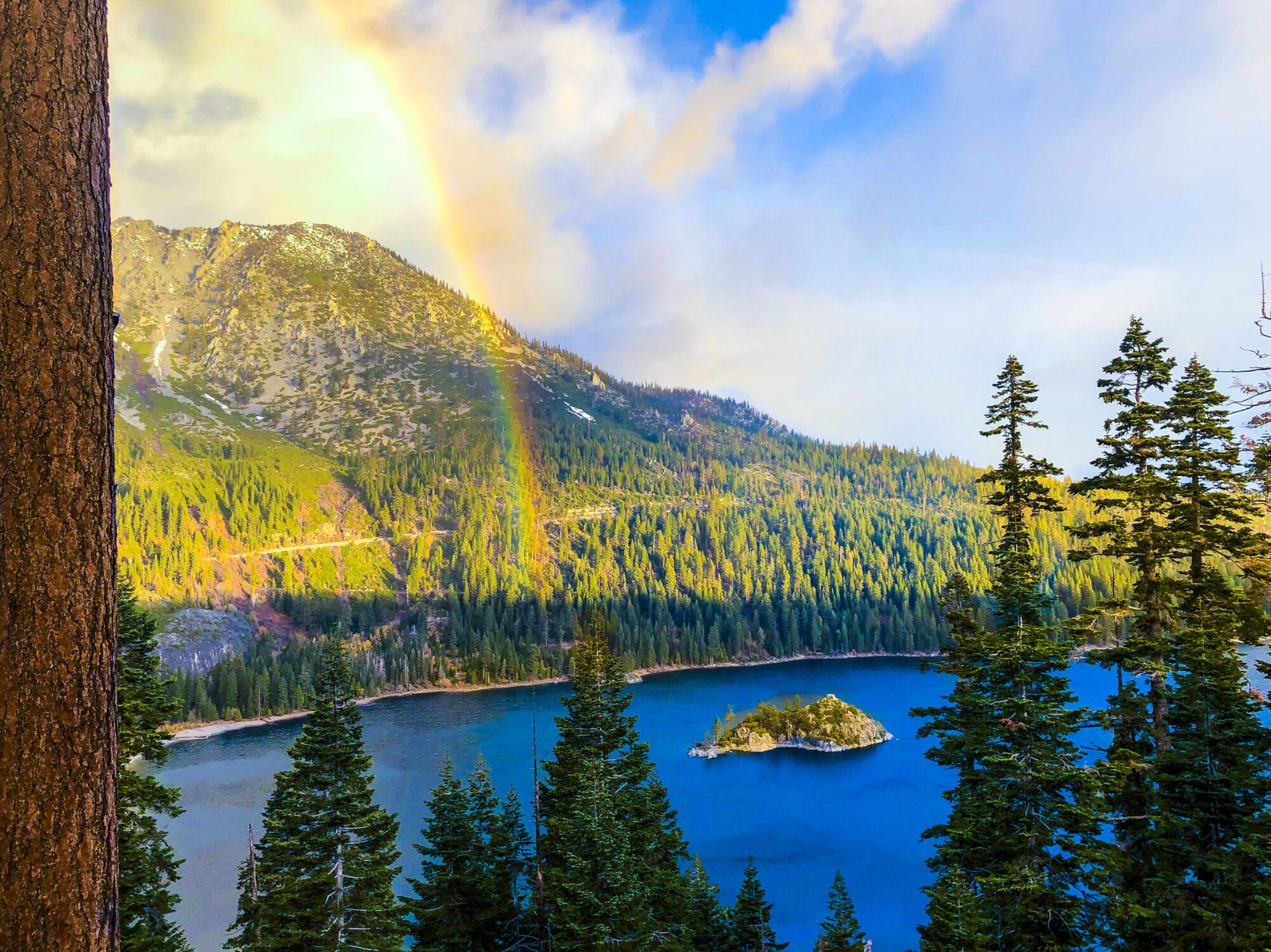 A sunrise over Lake Tahoe's Emerald Bay with billowing clouds and rainbows.