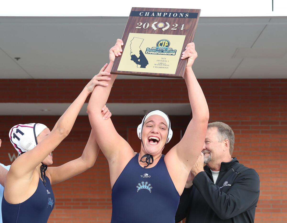 Corona del Mar's Ava Schoening holds up the trophy with teammate Reagan Weir (11) on Saturday.