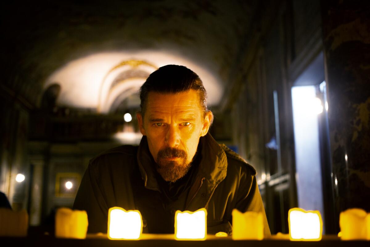 Ethan Hawke stares at a row of burning candles.